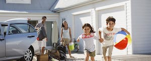 Young family in front of their Airbnb rental, children holding hands and running toward the camera
