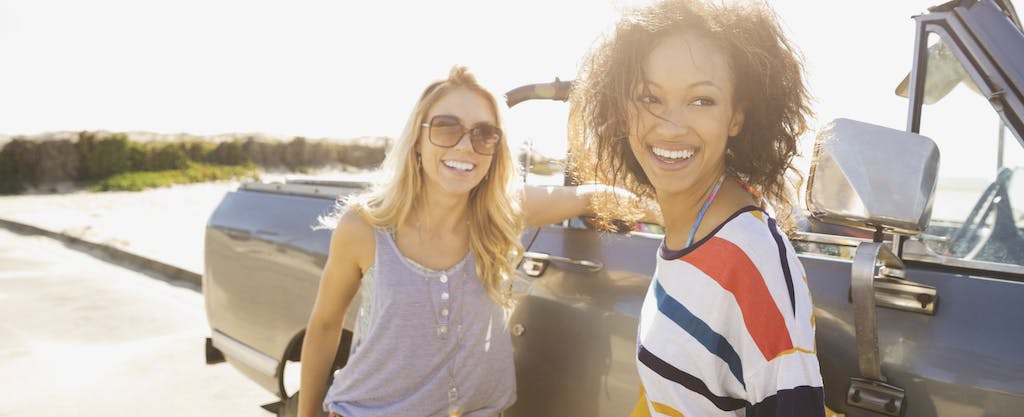Two female friends standing by car