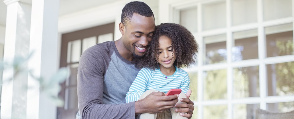 Father and daughter using cellphone on porch to look up where to get a major purchase loan