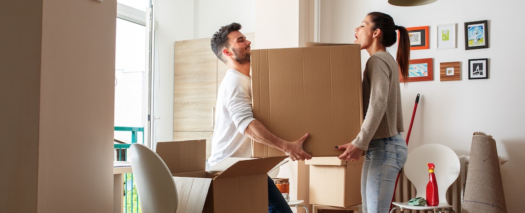 Couple carrying a big box together, moving into their new home