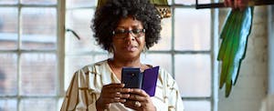 A woman with a thoughtful expression uses her smartphone to look into the details of a US Bank Checking account.